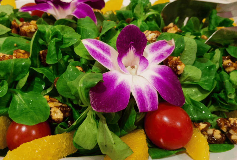 Frischer Feldsalat mit knackigen Walnüssen und dekorativen essbaren Blumen, angerichtet von Alexander O. Barth für ein exklusives Catering.